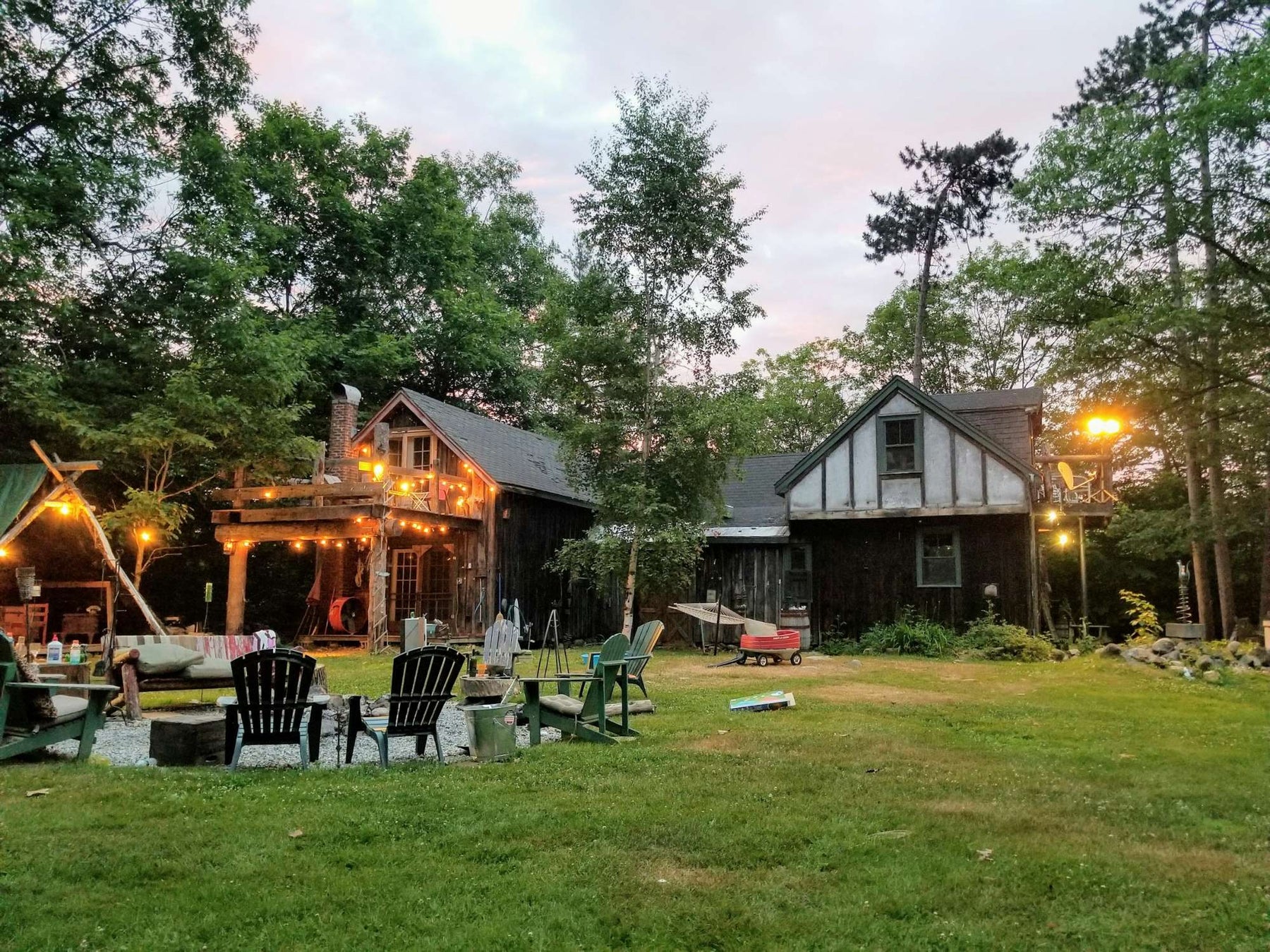 A charming countryside home with a well-lit outdoor gathering space, fire pit, and comfortable seating highlights the essence of Modern Indoor Outdoor Living