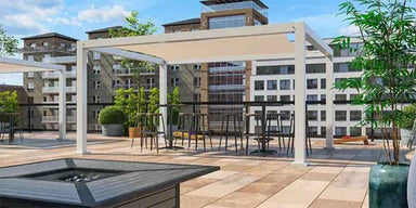 A black Structureworks Solis Trex Pergola with a decorative privacy wall provides shade over a stylish outdoor sofa set