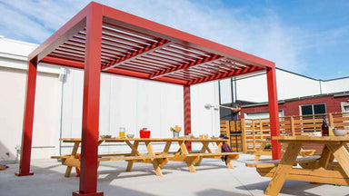 A cozy seating nook with two chairs sits peacefully under a white Structureworks Element Trex Pergola on a standalone raised deck in a grassy yard