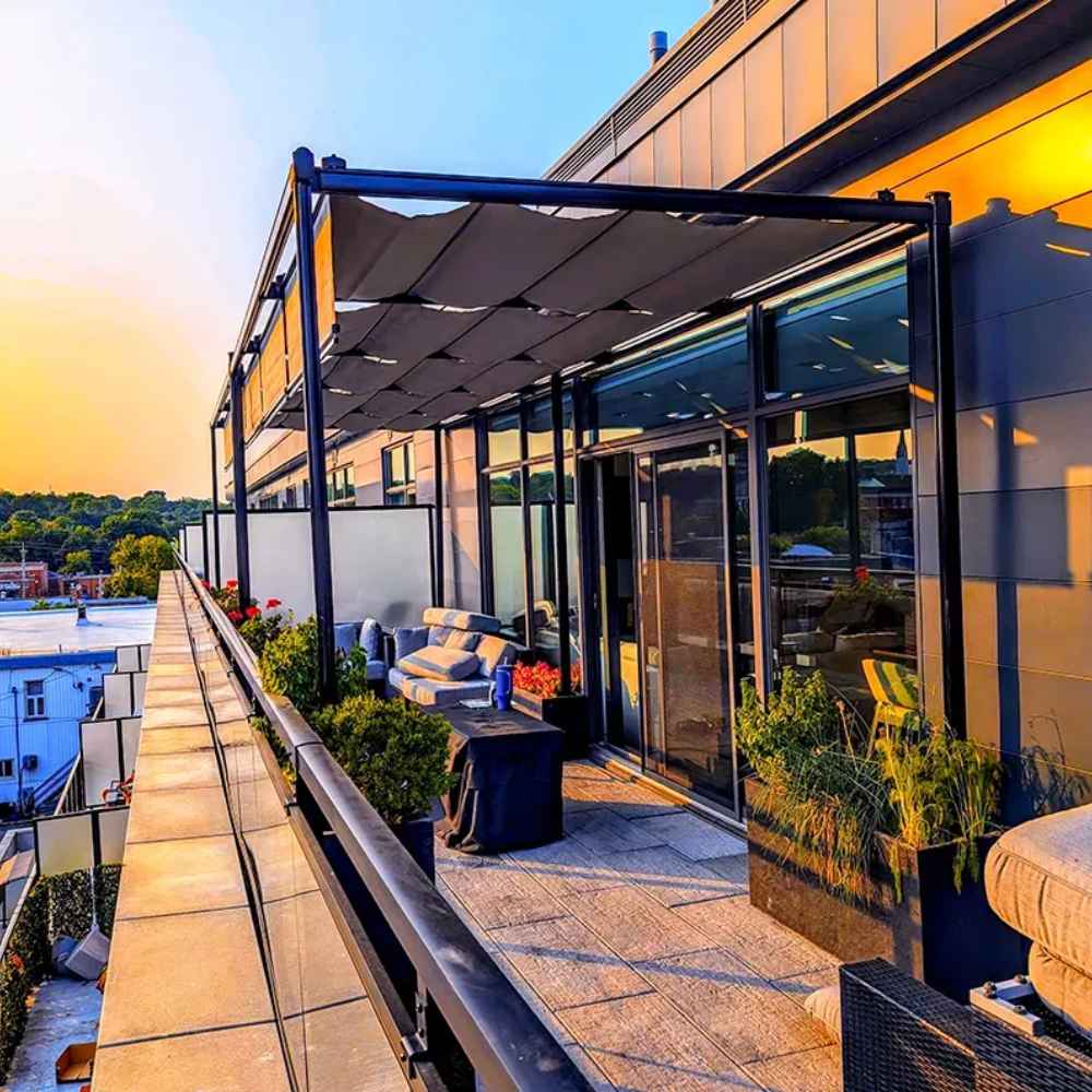 A sunset view enhances a rooftop deck with a contemporary Structureworks Silhouette Aluminum Patio Cover & Pergola over lounge furniture and potted plants
