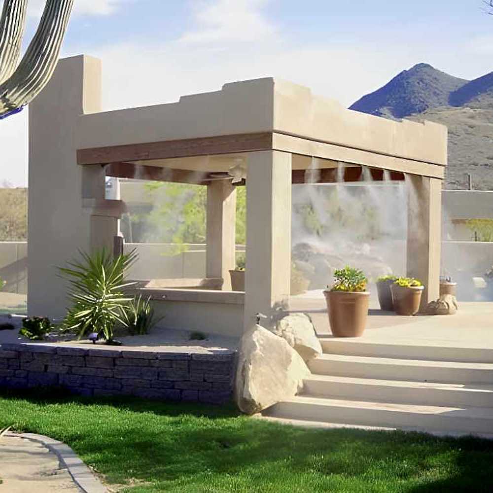 A beige outdoor gazebo surrounded by plants uses the Aeromist Pinnacle 1000 PSI Misting System to release a fine mist from the roof edges