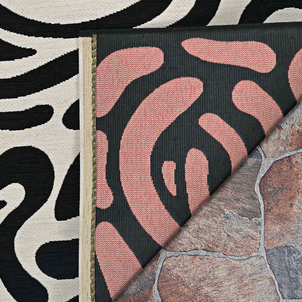 A close-up image shows the front and back of the Couristan Castille Indoor/Outdoor Rug - Graffiti/Black-White, highlighting its textured black and white pattern with a peek at its reverse side