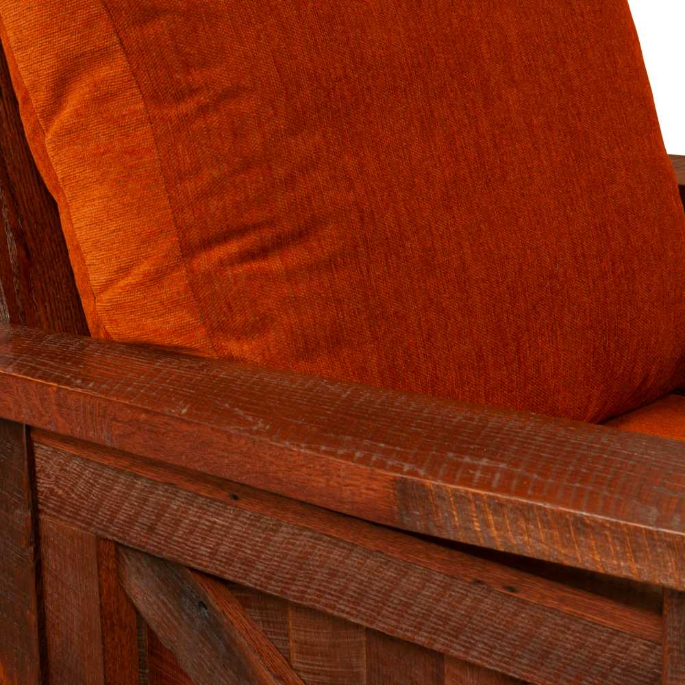 A close-up of the Fireside Lodge Barnwood Lounge Chair armrest shows rich, textured wood next to a burnt-orange cushion