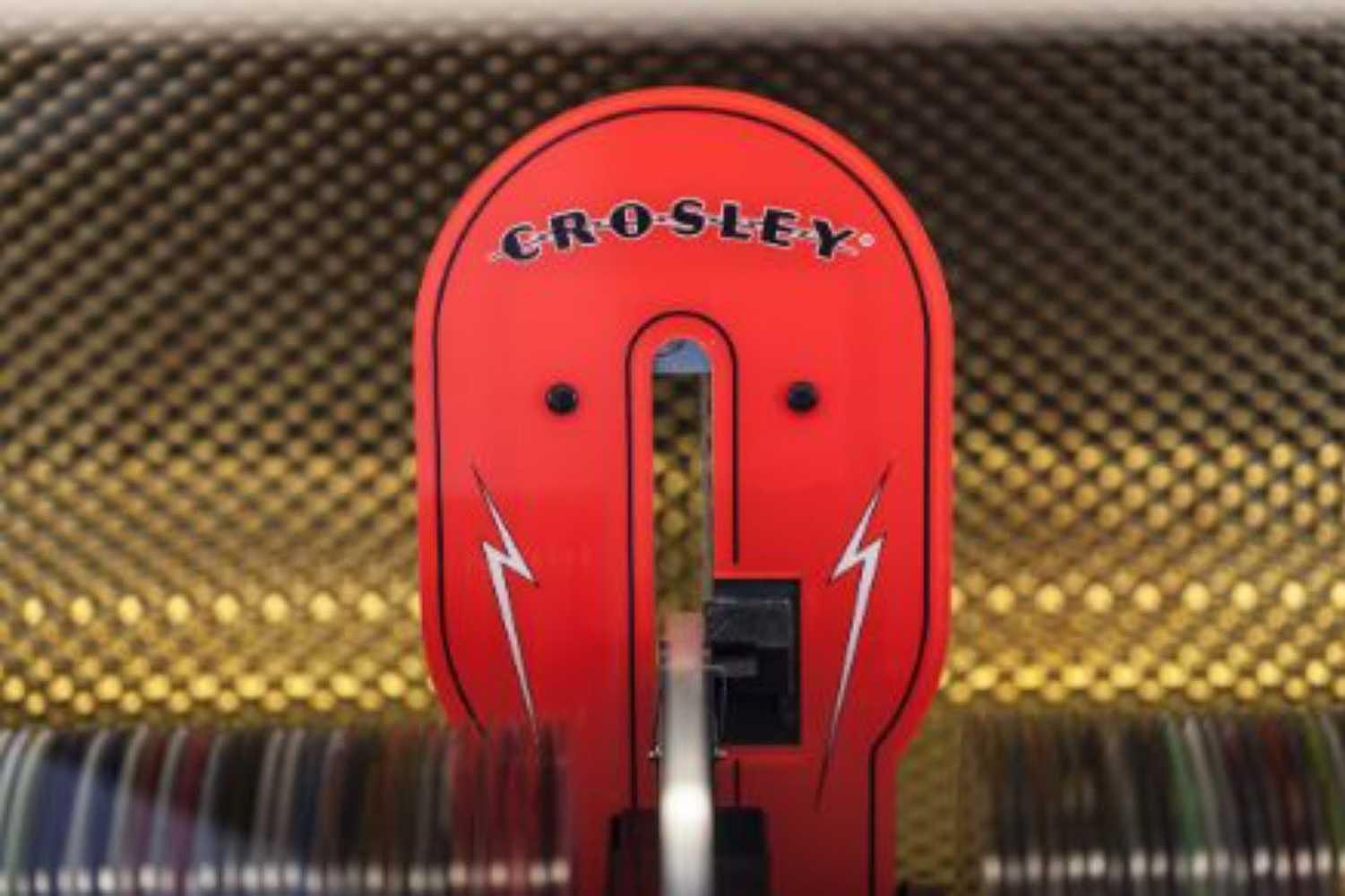 A close-up of the Rocket 80 CD Bluetooth Full-Size Jukebox - Turquoise highlights the bold red Crosley emblem set against a golden grill