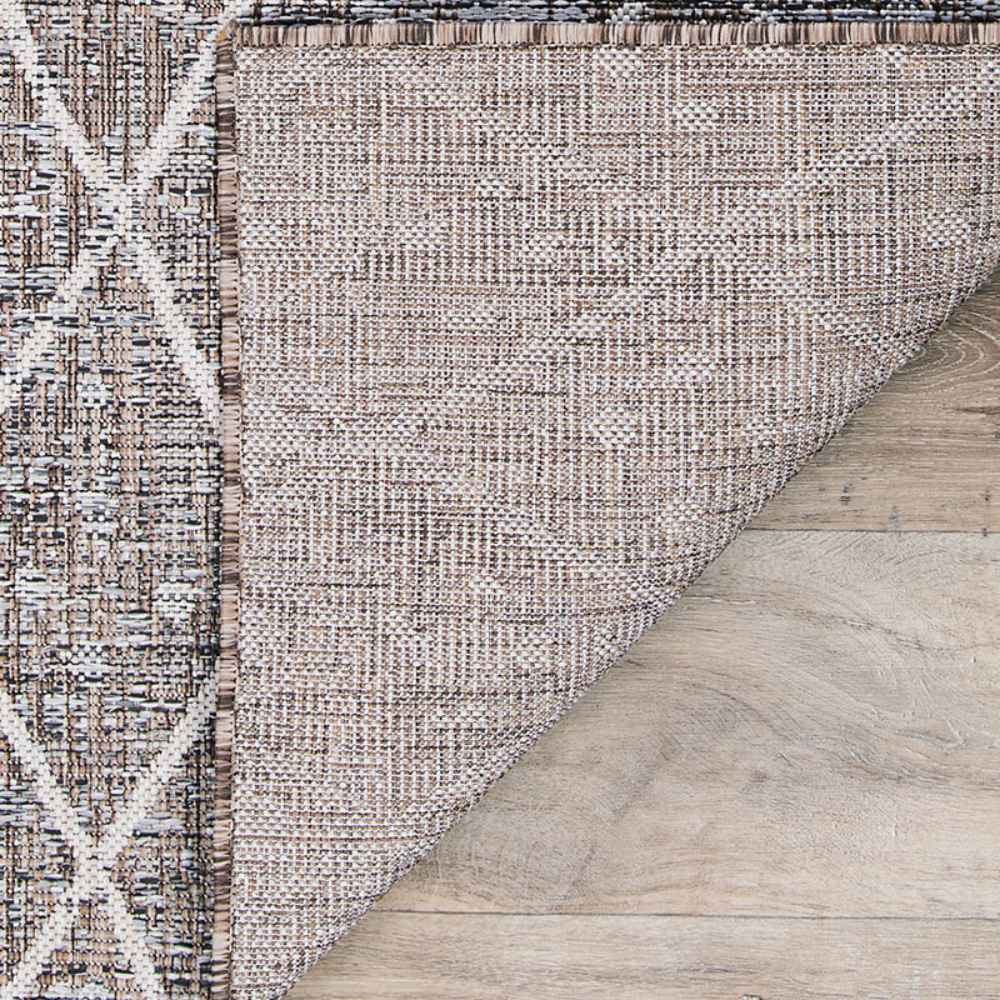 A close-up view shows the underside and weave texture of the Couristan Charm Indoor/Outdoor Rug - Thicket/Twig, highlighting its durable and tightly woven backing