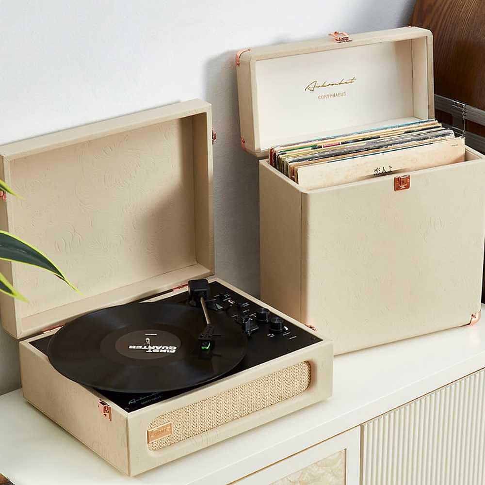 Arkrocket Coryphaeus Bluetooth Record Player with Record Storage Case (Flora Engraved) in a cream color with a stack of vinyl records stored neatly next to it