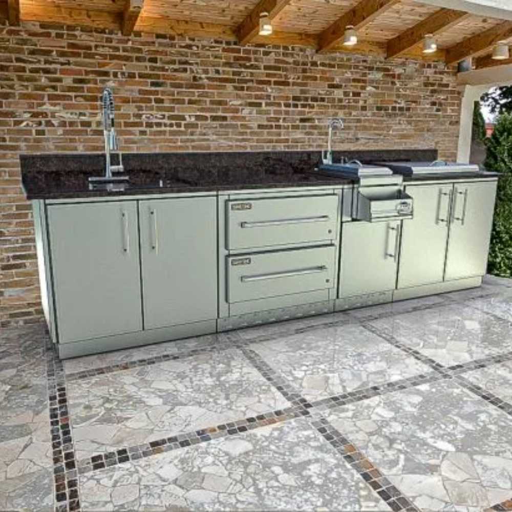 A stylish outdoor kitchen setup with brick walls and tiled floors features the Sunstone Galley 10ft 8in Clean & Prep Cabinet Island Package in a covered patio