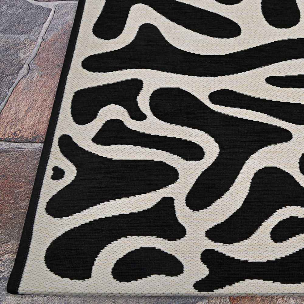 Couristan Castille Indoor/Outdoor Rug - Graffiti/Black-White lies on a stone floor
