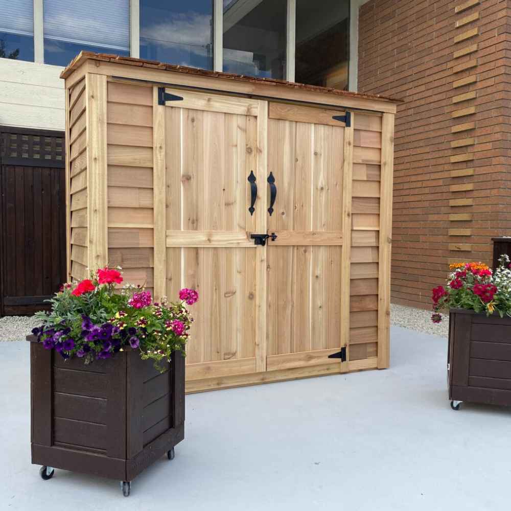 Placed against a brick wall and windowed home, the Outdoor Living Today Grand Garden Chalet with cedar roof