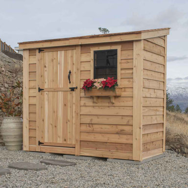 Single Door Cedar Roof Outdoor Living Today 8×4 SpaceSaver Lean-To Cedar Shed pictured with bright poinsettias in the window box, clean wood paneling, and a tidy gravel base near a stone wall