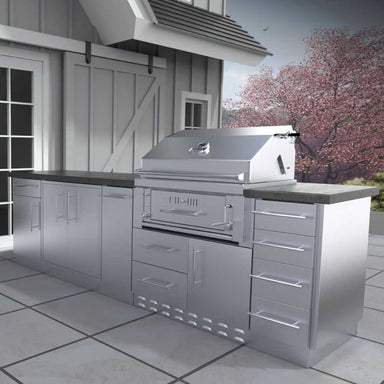 Sunstone Alamo 9ft Outdoor Hybrid Gas Charcoal Grill & Cabinet Island Package sits neatly under a covered patio beside sliding doors and springtime trees in bloom