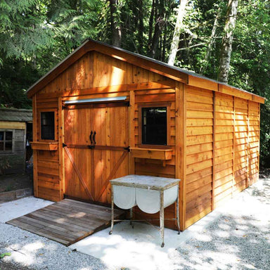 Surrounded by lush greenery, the Outdoor Living Today 12×12 Double Door Space Master Storage Shed displays a warm cedar exterior, dual doors, and rustic charm