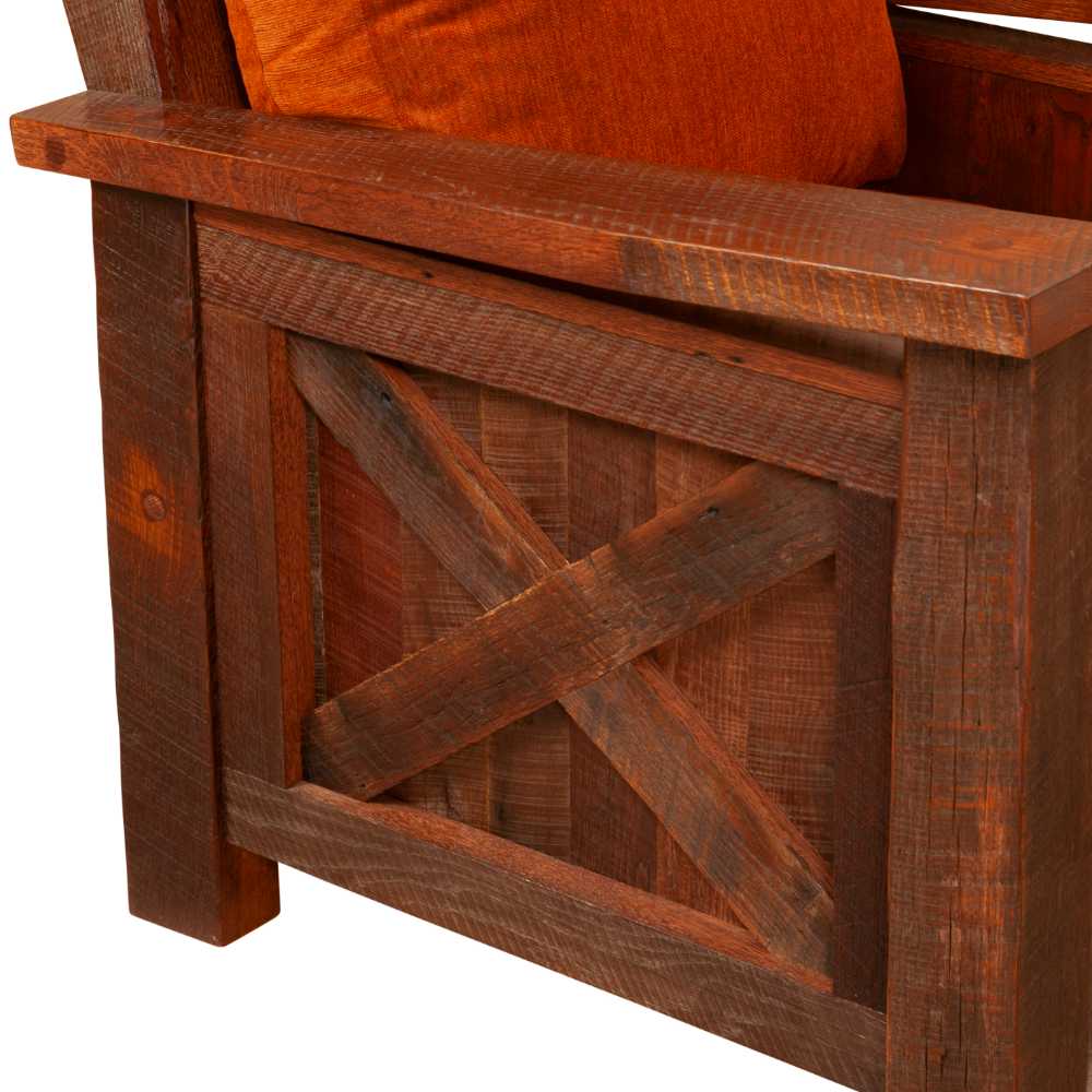 This close-up of the Fireside Lodge Barnwood Lounge Chair highlights the side panel's wood grain and X-frame detail beneath an orange cushion