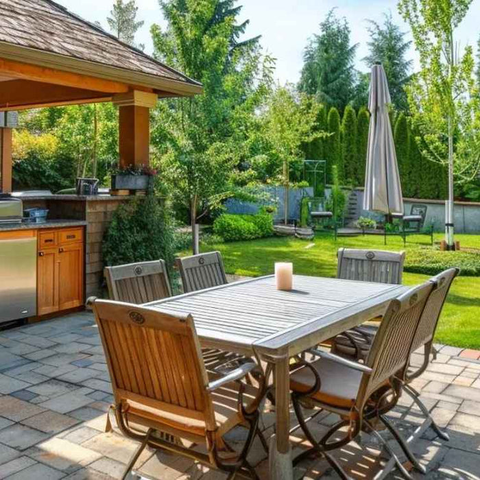 A backyard outdoor kitchen with a built-in grill, stainless appliances, and a dining table showcases stylish ideas from the Top 10 Backyard Essentials for 2025