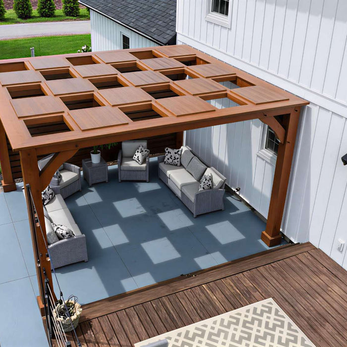 A backyard patio features a square wooden pergola with a patterned open roof casting shadows on the ground, demonstrating what is a pergola in a real home setting