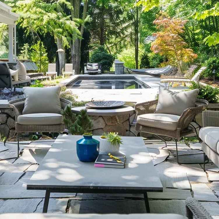 A shaded lounge area under a white pergola with hanging planters and a built-in grill, perfect for Easy Summer Decor Ideas for Your Outdoor Space