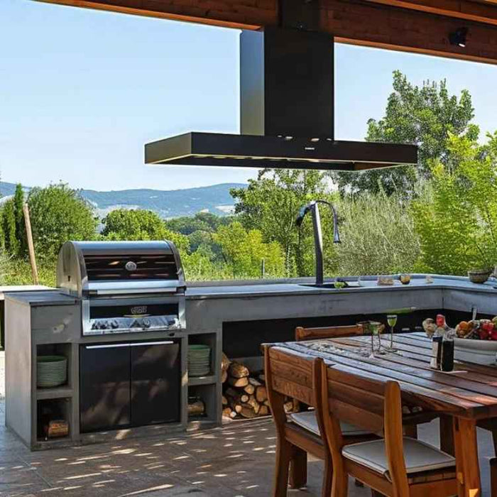 A shaded outdoor kitchen with a stone wall, grill, dining table, and open green views shows how to build an outdoor cooking station that blends comfort with function
