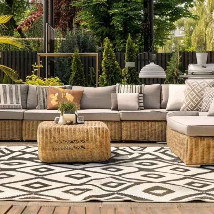 A sunny outdoor lounge with plush cushions, a rattan coffee table, and leafy greenery captures one of the 10 Outdoor Living Space Ideas for Summer that’s easy to recreate
