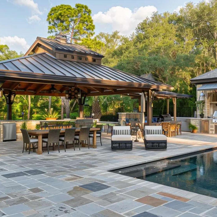 Luxury backyard with covered dining areas, an outdoor kitchen, stone patio, pool, and lush trees shows a backyard property value boost