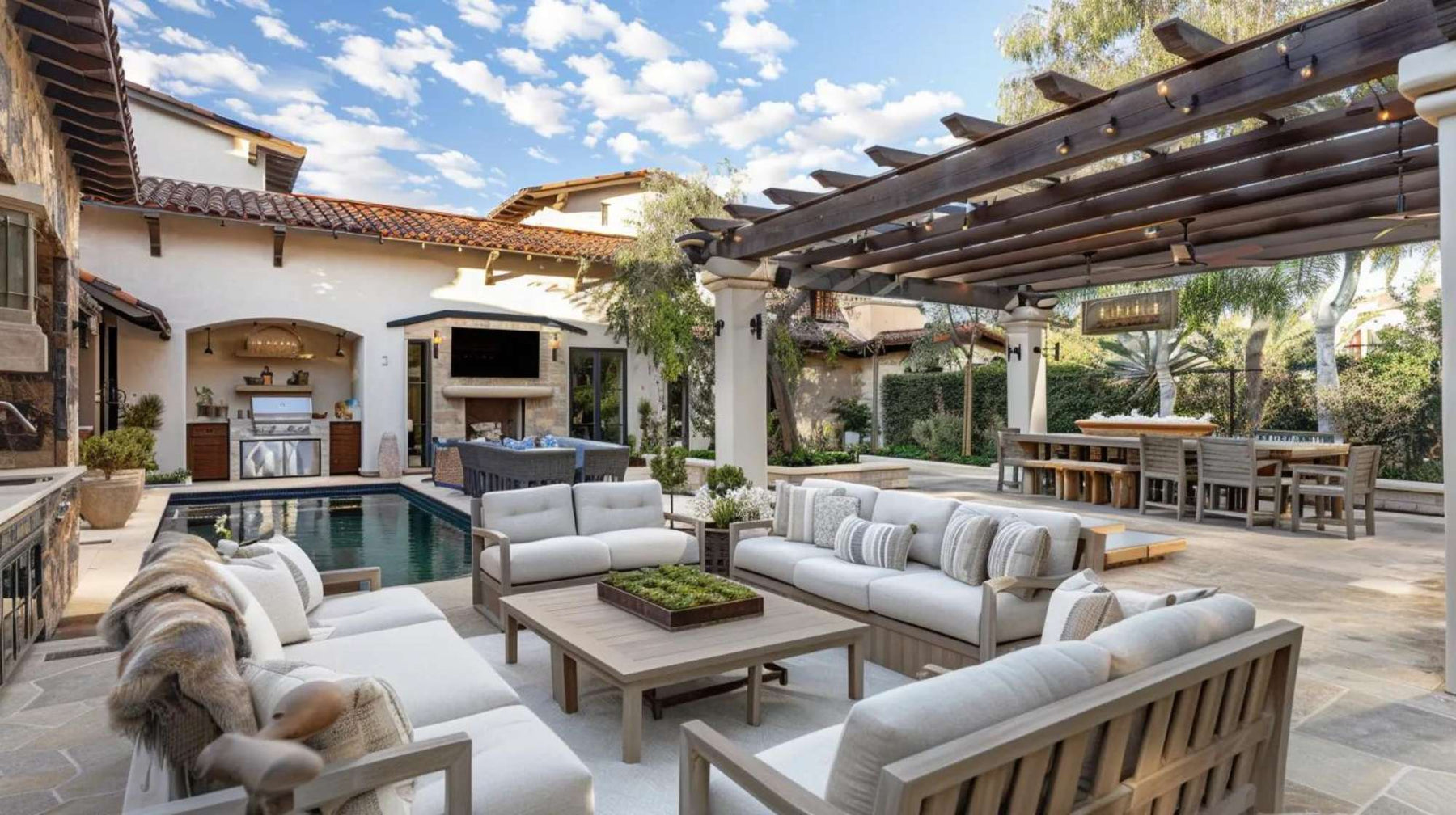 Luxury outdoor living furniture arranged around a poolside patio with cushioned sofas, a pergola dining area, and an outdoor kitchen in a modern backyard
