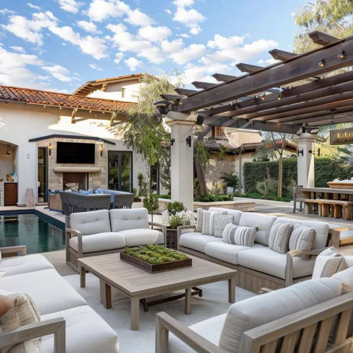 Luxury outdoor living furniture arranged around a poolside patio with cushioned sofas, a pergola dining area, and an outdoor kitchen in a modern backyard