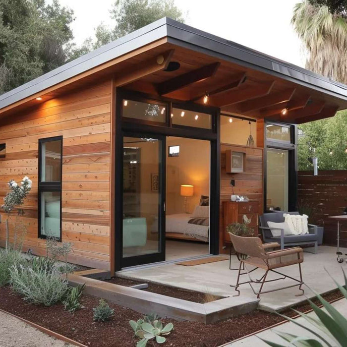 Military housing tiny home rental featuring a modern backyard ADU with wood siding, large glass doors, a private patio, outdoor seating, and landscaped surroundings