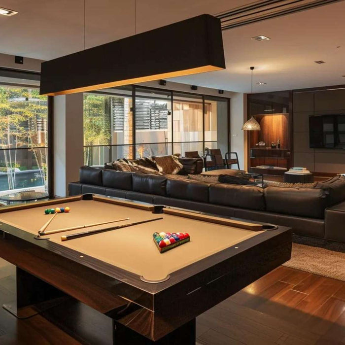 Modern man cave with pool table showing a sleek billiards table, black leather sofa, warm wood floors, and large windows letting in natural light.