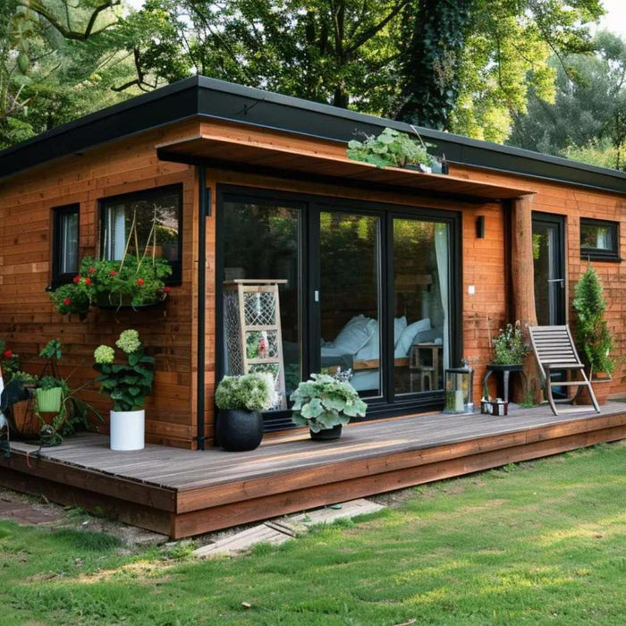 Modern wooden garden house with storage featuring large glass doors, a flat roof, and a deck surrounded by greenery