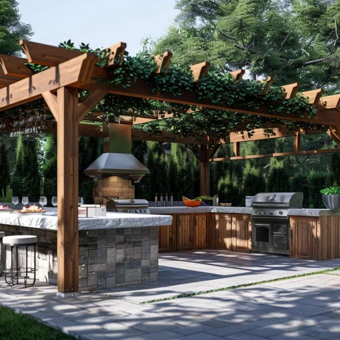 Outdoor kitchen setup beneath a wooden pergola featuring two built-in grills, a large stone island with bar seating, and surrounding greenery