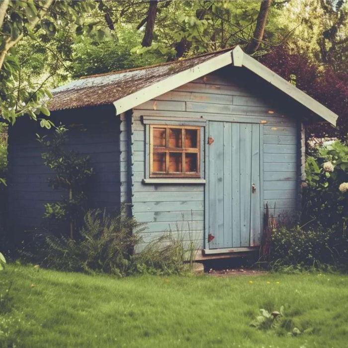 Small blue wooden garden building surrounded by trees and greenery, showing a simple passive income shed placed in a quiet backyard