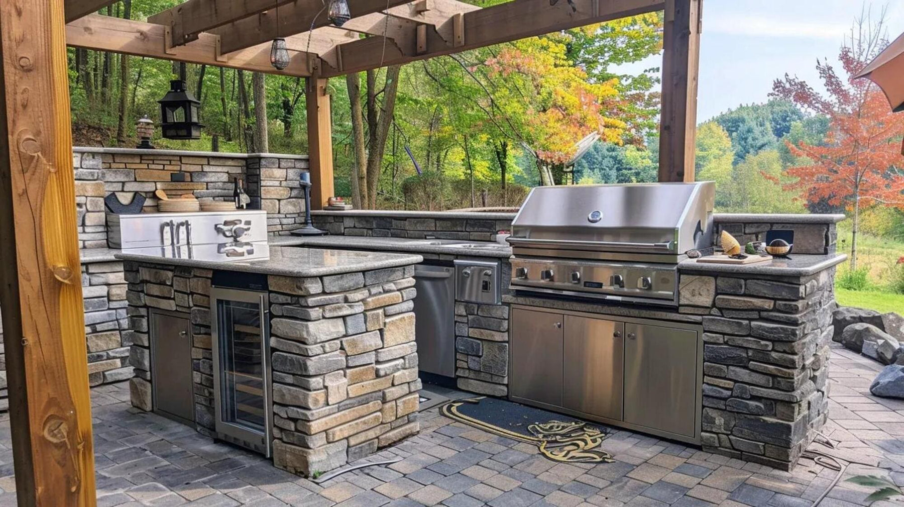 Stone outdoor kitchen with a stainless steel grill, mini fridge, counters, and wooded views creates a polished man cave BBQ setup