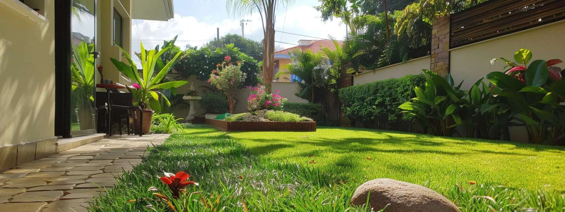 Sunny backyard with green lawn and a small raised flower bed, showing how build raised garden beds in a home garden