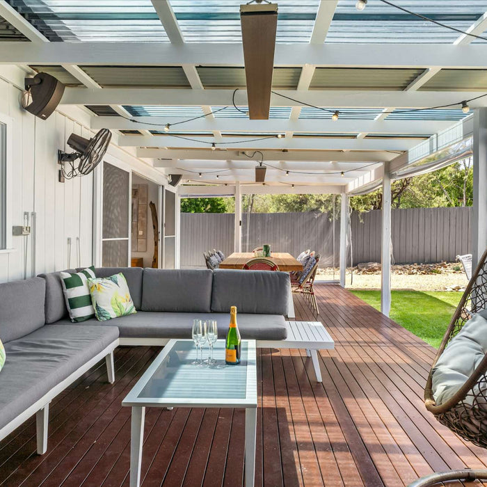 The image shows a covered patio with a dining table and string lights, highlighting another of the 15 Ways to Make Your Backyard Summer-Ready by creating a versatile outdoor dining space