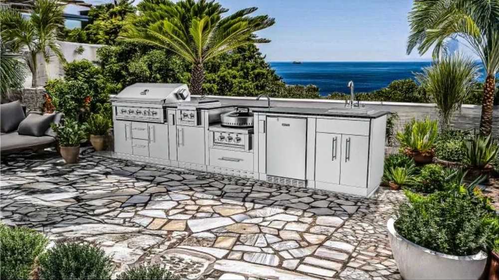 Sunstone Hill Country 13.6ft Outdoor Grill & Cabinet Island Package is set in a tropical patio with ocean views, surrounded by lush greenery and stone flooring