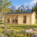 Small wood cabin with glass doors and windows in a grassy field with mountains in the background.