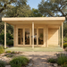 Rectangular wood studio with glass doors and a porch, nestled among trees with two people working inside at a desk.