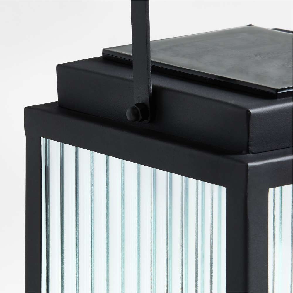 13 inch Crate & Barrel Alfresco Black Metal and Glass LED Solar Outdoor Lantern in an alternate view showing the removable solar panel on top
