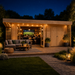 Wooden Konrad 44 cabin at night with string lights, outdoor patio furniture, and people watching a screen inside.