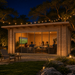Rectangular wood studio with glass sliding doors at night, featuring people sitting inside a lit room watching television.