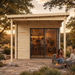 Light wood rectangular studio with sliding glass doors, interior bar, and people sitting on a stone patio at sunset.