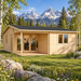 One light wood Skanderborg 70 cabin with a black shingle roof, set in a meadow with mountains in the background.