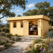 Rectangular light wood studio with double doors open to an office interior, set in a garden with a stone path.