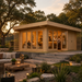 Rectangular wood Konrad 44 cabin with glass doors and windows, illuminated at dusk with people inside and a patio lounge.