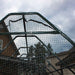 A close-up of the black mesh roof on Outdoor Living Today 8×12 Raised Garden Bed shows the frame arching over the garden against a cloudy sky