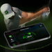 A golfer practicing their swing with a smartphone displaying club speed data from SKYTRAK ST MAX Launch Monitor