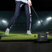 A golfer swinging a club on a practice mat with SKYTRAK ST MAX Launch Monitor positioned beside the hitting area