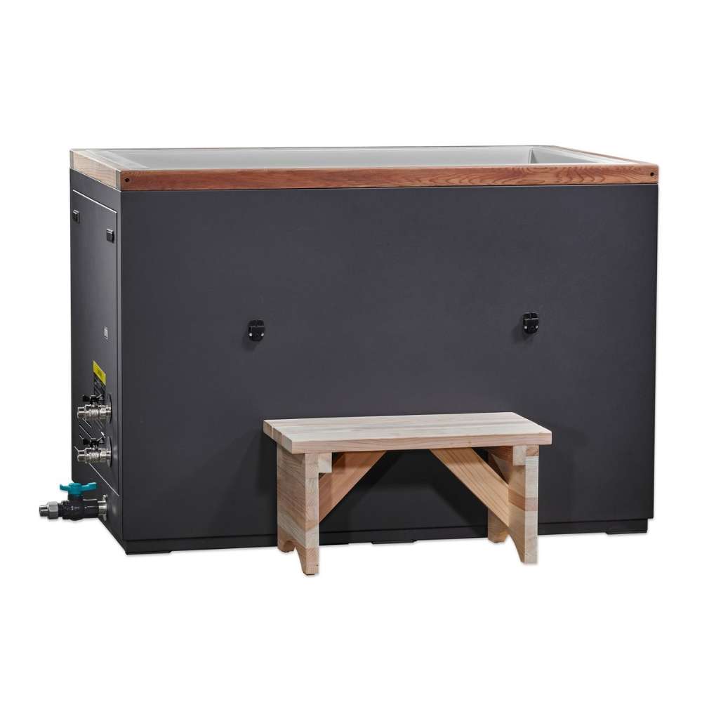 A light wood step sits in front of Golden Designs Dynamic Cold Therapy Cuboid Plastic Cold Plunge Tub, a dark gray rectangular cabinet with cedar trim along the top