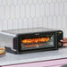 A pizza cooks inside Instant Pot® InstantHeat™ Pizza Oven while a hand adjusts the control dial to 400°F
