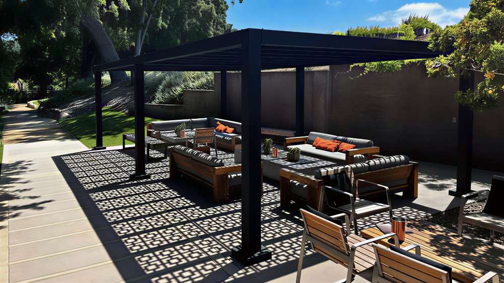 A sleek black Structureworks Shadow Trex Pergola stands over a stylish outdoor seating area with cushioned chairs and sofas