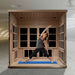 A woman holds a yoga pose on a blue mat inside Golden Designs Catalonia 8 Person Near Zero EMF Far IR Sauna with its benches removed